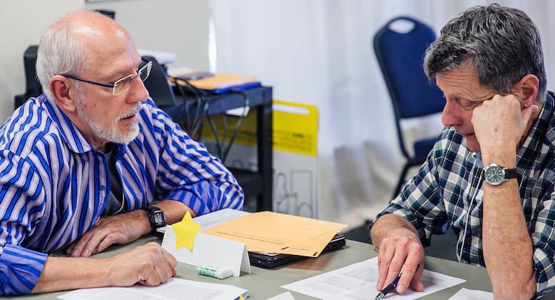 Two older white men discuss paperwork