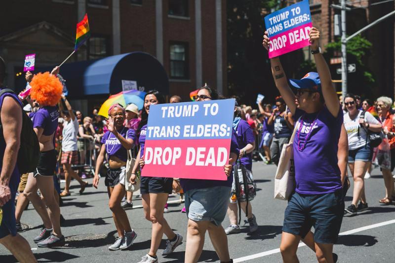 LGBTQ+ Pride marchers for SAGE hold signs in support of transgender elders