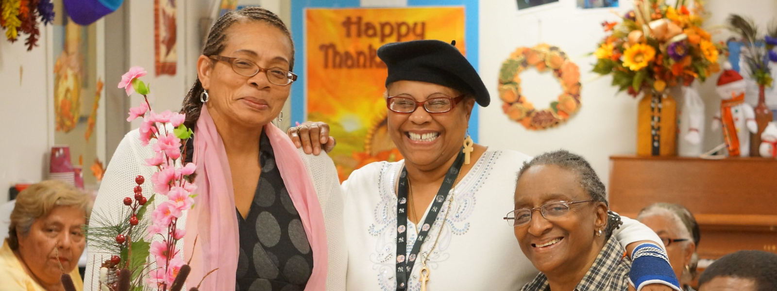 3 elders standing side by side smiling. 