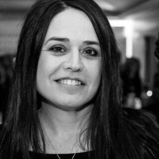 Smiling woman with long dark hair in a black and white photo.